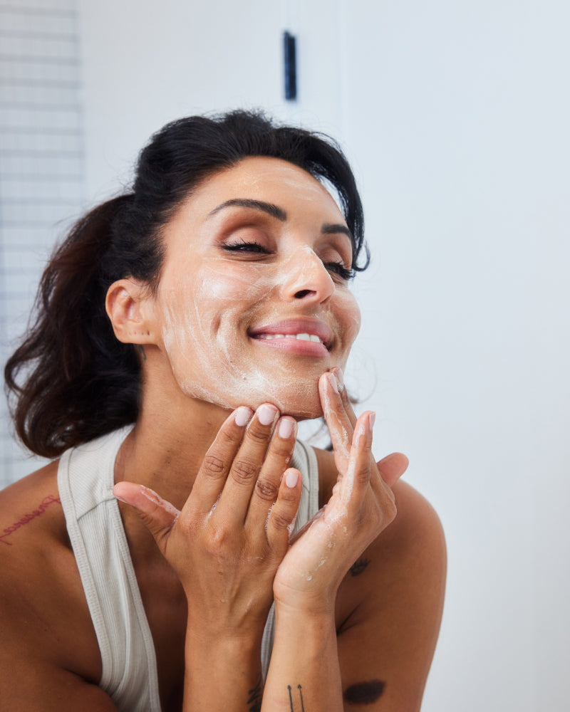 Woman gently cleansing face with 3-Step Glow Trio foaming cleanser in gallery position 1 for hydration routine